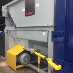 Auger-Pak™ EM-60W, Open at a Dock Platform, Rear Feed Flip Hopper, Forklift and Hand-fed, with Attached Container, Outside View