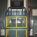 Quad-Shaft Electromechanical Shear Shredder, Auger-Pak™ EM-15G, installed inside view of vertical lift cart tipper and chute opening.